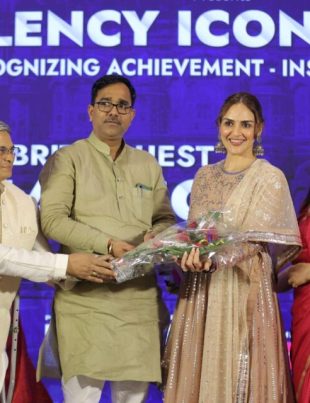 Four individuals standing on a stage during an award ceremony, with one person handing a bouquet to another Bizz Expo & Summit.