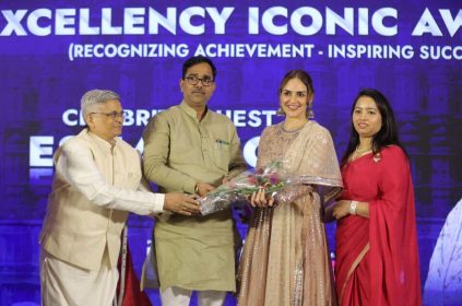 Four individuals standing on a stage during an award ceremony, with one person handing a bouquet to another Bizz Expo & Summit.